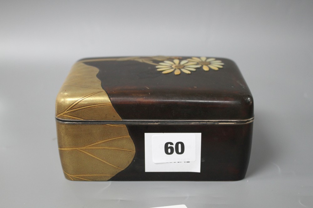 A Japanese Meiji period lacquer box, decorated with lotus leaves and flowers, with the petals inset with mother of pearl, silver rim an